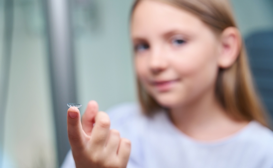 Kind hält Kontaktlinse in der Hand. 